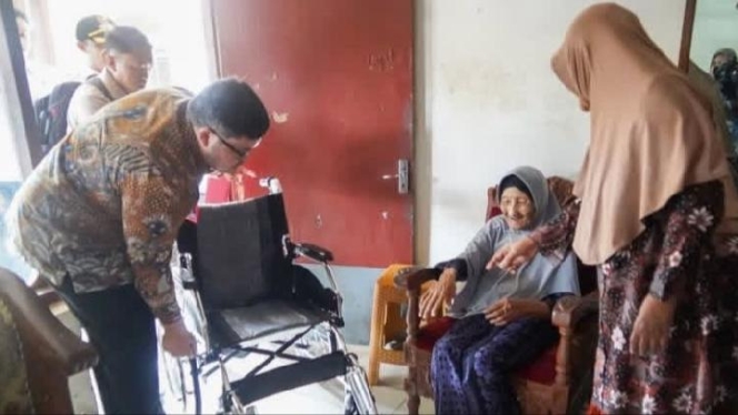 
 Bupati Kediri Hanindhito Himawan Pramana saat menyerahkan bantuan kursi roda kepada Mbah Marsiyah, jamaah haji tertua di Kabupaten Kediri. (Foto: RSS)