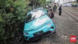 Petugas kepolisian saat melakukan olah TKP dan investigasi pada unit taksi listrik Green SM yang mengalami kecelakaan di perlintasan sebidang. (Foto: RSS)